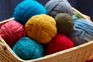 Balls of knitted wool in basket, closeup